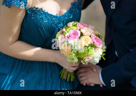 Sposa che indossa un vestito blu e lo sposo alle nozze con focus su sposa mani grandi bouquet rotondo con color pastello di rose Foto Stock