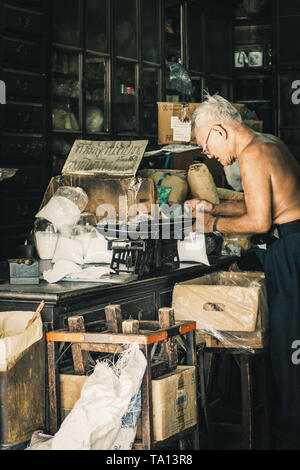 China town di Bangkok in Thailandia Dicembre 2018 vecchio uomo cinese nel negozio di erbe Cinesi o negozio di erbe essiccate in legno armadio antico e storage per medical d Foto Stock