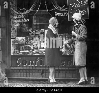 Conversazione tra due donne di fronte a mom-e-pop shop. Foto Stock