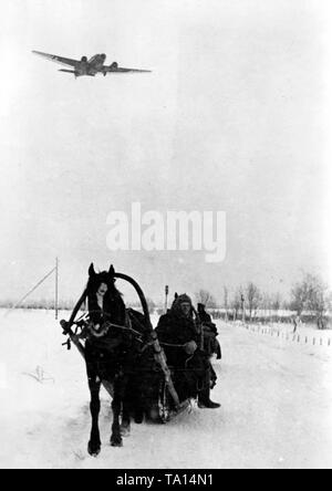 I soldati tedeschi un giro in slitta su una coperta di neve strada vicino alla città di Demyansk. Al di sopra di essi, un flying JU 52 (La foto è stata scattata nel gennaio del 1942, in modo da non rappresentare un volo parziale del ponte aereo, che aveva fornito i soldati intrappolati per quasi due mesi in tasca). Foto di Propaganda Company (PK): corrispondente di guerra Beissel. Foto Stock