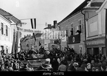 Adolf Hitler visite villaggi austriaca sul suo modo di Vienna, dopo il Anschluss (annessione) dell'Austria per il Reich tedesco. La strada è decorata con bandiere con la svastica e il poster recita: 'salutiamo il nostro Fuehrer!". Foto Stock