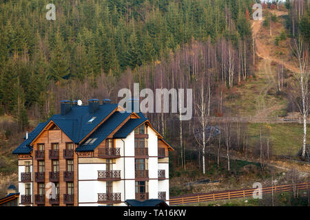 Nuovo moderno e confortevole hotel a quattro piani edificio con annesso locali, camere attico e alte ciminiere in ecologica area rurale su abete rosso di una densa foresta Foto Stock