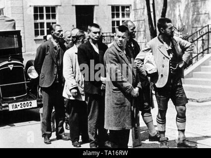 Un gruppo di arrestati casualmente persone (alcuni in costumi tradizionali) arrivano a nuova costruzione campo di concentramento di Dachau nella primavera del 1933. Foto Stock