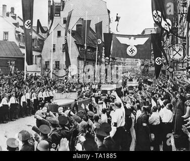 Adolf Hitler entra in una città nel Sudetenland occupato. Il suo per il giro della Papamobile è accolto festosamente dalla popolazione. Essi lo saluto con il saluto nazista. Foto Stock