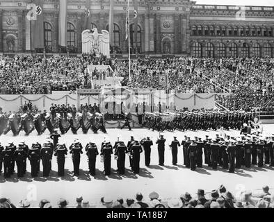 Foto del VIP stand durante la sfilata per la Legione Condor sull'asse est-ovest (ex Chalottenburger Chaussee, oggi Strasse des 17. Juni) davanti alla facciata principale della Technische Universitaet di Berlino del giugno 6th, 1939. Adolf Hitler (sotto una tettoia) sta dando la marching soldati il saluto nazista. A sinistra sotto la Reichsadler (Imperial Eagle) con una croce uncinata, un commentatore radio. La banda musicale della Kriegsmarine (marina da guerra) è in corso di riproduzione. Foto Stock