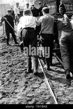 Lavoratori spingere via un carrello con sporcizia sui binari. Non datata (foto). Foto Stock