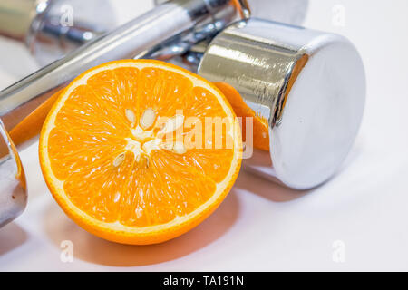 Sport concetto di formazione, manubri peso con nastro di misurazione, arancione e frutto di Apple su bianco vintage sfondo di legno Foto Stock