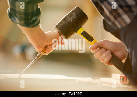 Primo piano di un irriconoscibile carpenter colpendo chiodo con un martello durante il lavoro in falegnameria, spazio copia Foto Stock