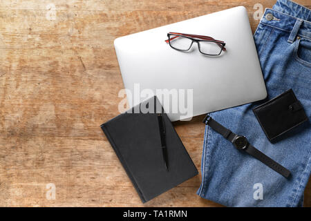 Eleganti Jeans maschio, laptop e accessori su sfondo di legno Foto Stock