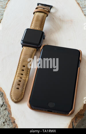 Progetto generico smartwatch e smartphone con custodia in vera pelle e cinturino su sfondo di legno.Shallow DOF Foto Stock