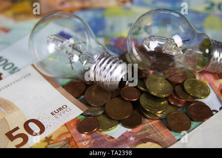 VIERSEN, Germania - 20 maggio. 2019: alimentazione il concetto di costo - lampadine elettriche sulla carta Euro money bank note e pila di monete Foto Stock