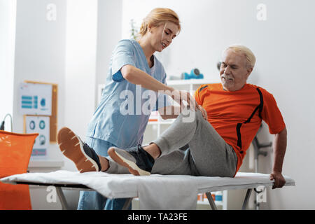 Bella donna bionda di toccare i suoi pazienti ginocchio Foto Stock