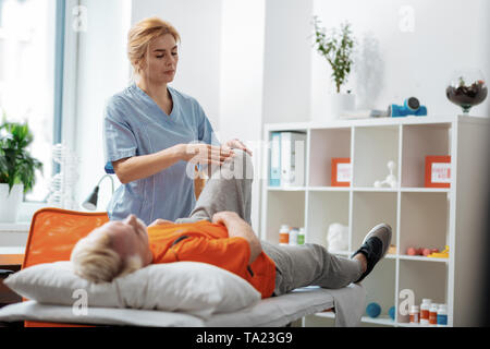 Grave bella donna di toccare i suoi pazienti ginocchio Foto Stock