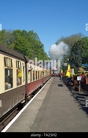 Vista la piattaforma dei Vescovi Lydeard stazione ferroviaria nel Somerset, Regno Unito, con un treno vintage circa per lasciare. La foto è stata scattata in Somerset giorno 2019. Foto Stock