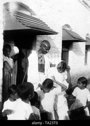 Il leader dell'Indiano movimento di indipendenza, il Mahatma Gandhi, lasciando una scuola. Foto Stock