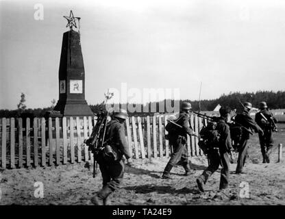 Il tedesco di fanti passano da un monumento sovietico con la falce e martello sulla loro marcia verso Stalingrado. Uno dei soldati si è assunta una mitragliatrice 34, il suo compagno di fronte a lui sta portando la canna di ricambio e la scatola di munizioni. Il soldato a sinistra porta il carrello della pistola. Corrispondente di guerra: Kipper. Foto Stock