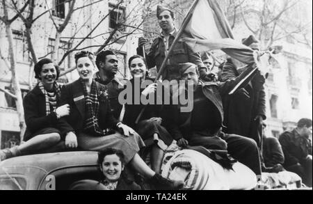 Nazionale spagnolo di soldati celebrare su un carrello poco dopo la conquista di Barcellona dal generale Franco su La Rambla (passeggiata in centro città con giovani residenti di Barcellona nel mese di gennaio, 1939. Una donna ridere mantiene la nazionale spagnola di bandiera (Bandera, rosso-giallo-rosso). Foto Stock