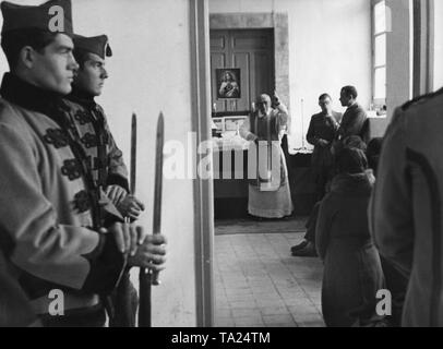 Foto di Cattolica la Messa domenicale per reclute della nazionale spagnola di truppe in una baracca a Salamanca il 16 dicembre 1936. Un sacerdote benedice i soldati davanti all altare e un'immagine di Gesù. Una donna si inginocchia davanti a lui. Due ufficiali stare sulla destra. In primo piano, i soldati in uniforme di parata e baionette a guardia della porta. Foto Stock