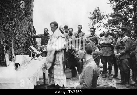 Foto di un servizio all'aria aperta per i soldati spagnoli a San Sebastian e Irun nel paese basco spagnolo. In primo piano - un sacerdote cattolico (indumento liturgico) di fronte a un altare su un muro di casa. I soldati si inginocchiano e sostare di fronte ad esso. San Sebastian, 24km a ovest di Irun e Hendaye, le città di confine di Francia, cadde nelle mani dei ribelli alla fine di luglio. Foto Stock