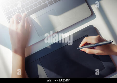 Graphic designer con tavoletta digitale e portatile con la luce solare Foto Stock