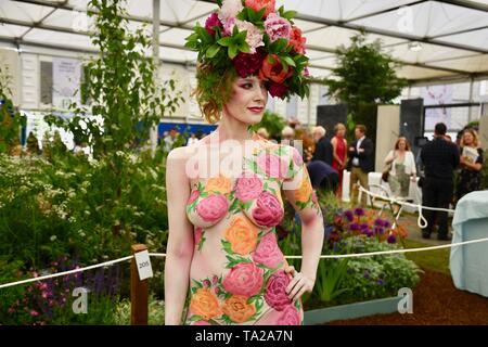 Un modello che indossa una ghirlanda di peonie e decorate con motivi floreali corpo art. RHS Chelsea Flower Show, premere giorno, Londra Foto Stock