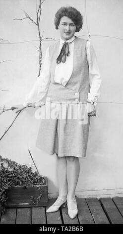 Una donna in posa di un mantello con abbinamento di giubbotto senza maniche e camicia bianca. Foto Stock