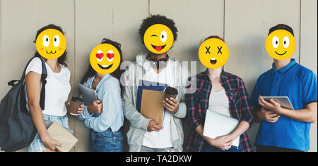 Gli studenti con facce emoji azienda libri su sfondo grigio Foto Stock