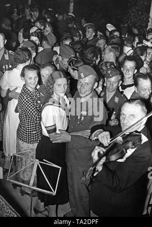 Foto di un gruppo di soldati della Legione Condor (esercito e Air Force) in uniforme e le donne da Berlino durante un ballo dopo la vittoria sfilata della truppa in Mitte (Berlino) la sera del 6 giugno 1939, in Doeberitz. L'allegro bivacco è stato organizzato dalla Legione e GFN "Kraft durch Freude". Vi erano bivacco falò, open-air e spettacoli di fuochi d'artificio. Un violinista è in primo piano. Foto Stock