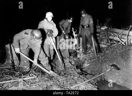 Soldati tedeschi sono scarichi di scavo con benne e asce per la comunicazione di trincee sulla parte anteriore. Grazie alla sua vicinanza alla parte anteriore, il lavoro potrebbe essere fatto solo di notte. Foto di Propaganda Company (PK): corrispondente di guerra Hilkenbach. Foto Stock