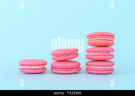 Amaretti rosa su sfondo blu. Concetti di classificazione e di crescita. Foto Stock