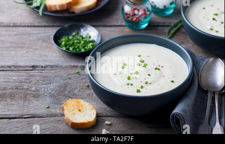 Il cavolfiore e crema di patate zuppa di cipolla verde in una ciotola di legno grigio Sfondo. Copia dello spazio. Foto Stock