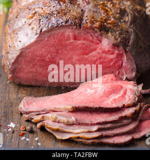 Arrosto di manzo sul tagliere. Sfondo di legno. Close up. Foto Stock