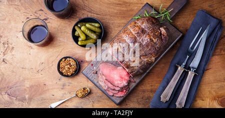 Arrosto di manzo sul tagliere. Sfondo di legno. Vista dall'alto. Foto Stock