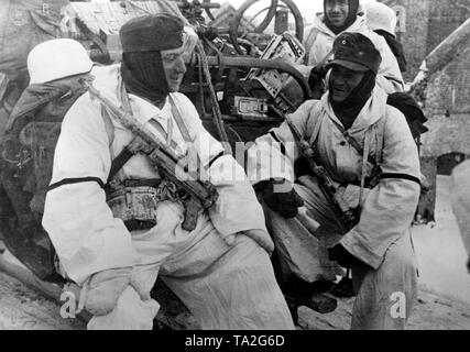 Soldati tedeschi sono in appoggio su un auto blindata di Smolensk. Con l'abbigliamento invernale e le pistole automatiche 40, che sono sulla loro strada verso la parte anteriore. Foto di Propaganda Company (PK): corrispondente di guerra Henisch. Foto Stock