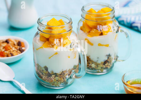 Mango fresco frutta con yogurt e granola in vasi. La pietra blu sullo sfondo. Close up. Foto Stock