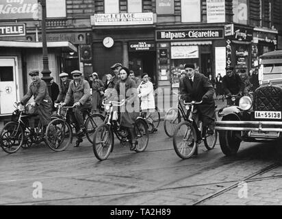 Ciclisti alle 08.00 del mattino nel traffico a Oranienburger Tor. Segni sul muro di casa in background di appartamenti e locali commerciali in affitto - spazi vuoti a Berlino durante la crisi economica mondiale. Foto Stock