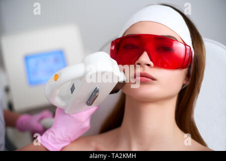 Estetista medico facendo RF laser-ringiovanimento per la bella giovane donna a un salone di bellezza. Elos cosmetologico capelli durante la procedura di rimozione. Viso estetici Foto Stock