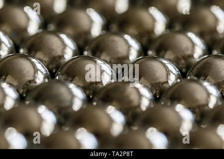 Close-up e prospettiva con la sfocatura di molti oggetti formando una struttura ordinata. Lucido metallo palle a sparare da un'imbracatura, uniformemente disposti. Foto Stock