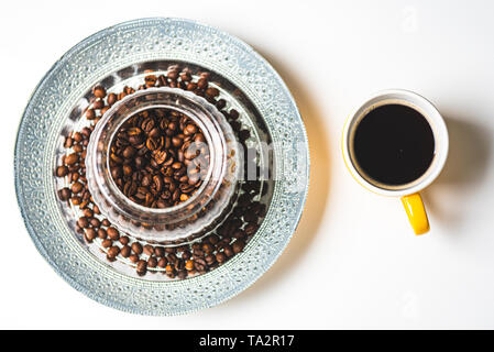 Ceramica di colore giallo tazza da caffè su sfondo bianco accanto al vaso con i chicchi di caffè. Espresso nero Foto Stock