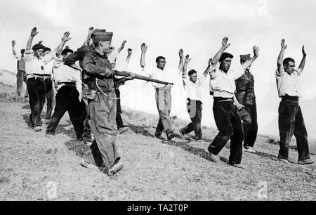 Foto di un gruppo di disarmati e arrestati combattenti comunista di Somosierra vicino a Madrid nel mese di agosto 1936, poco dopo lo scoppio della guerra civile spagnola. I combattenti che indossa pantaloni da lavoro, camicie bianche e berretti sono spinti verso il basso di una collina con le mani alzate da due soldati spagnoli, che sono armati con i moschettoni. Foto Stock