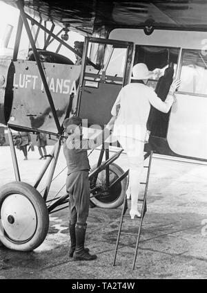 Un Lufthansa Flight attendant aiuta a un passeggero a bordo di un Fokker FII. Foto Stock