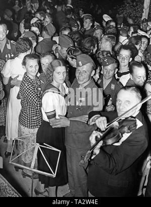 Foto di un gruppo di soldati della Legione Condor (esercito e Air Force) in uniforme e le donne da Berlino durante un ballo dopo la vittoria sfilata della truppa in Mitte (Berlino) la sera del 6 giugno 1939, in Doeberitz. L'allegro bivacco è stato organizzato dalla Legione e GFN "Kraft durch Freude" (organizzazione nazista "strenght attraverso Gioia"). Vi erano bivacco falò, open-air e spettacoli di fuochi d'artificio. In primo piano è un violinista. Foto Stock