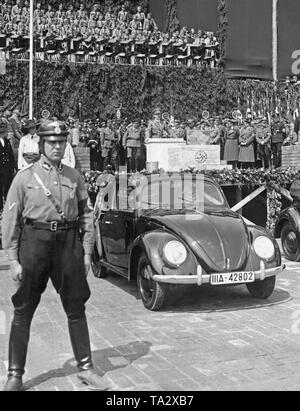 Hitler durante il suo discorso alla cerimonia di rivoluzionario dell'impianto VW nel 'Stadt des KdF-Wagens' (Città del KdF Auto), il seguito di Wolfsburg. In primo piano un soldato e due prototipi della vettura. Foto Stock