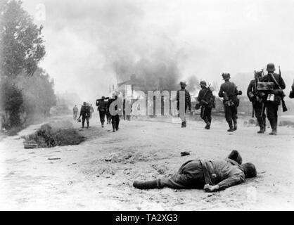 La fanteria tedesca su uno dell'anticipo strada ad est. I soldati in centro a sinistra porta un smontato lanciagranate Granatwerfer xxxiv in primo piano un caduto Red Army soldier. Foto Stock