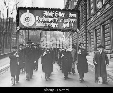 Nel corso dei Sudeti tedesco elezioni, membri della nazionale socialista la guerra della vittima (cura NSKOV) marzo attraverso Reichenberg (oggi Liberec). In plebiscito, voti sono espressi riguardante l'annessione dei Sudeti al Reich tedesco. Sul poster: 'Adolf Hitler - il restauratore del nostro soldato onore- heil !!". Foto Stock