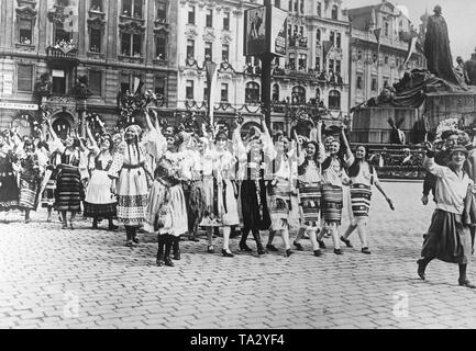 Paese di Moravian ragazze in costumi tradizionali al Sokol congresso a Praga. Le ragazze di salutare il Presidente cecoslovacco Tomas Garrigue Masaryk. Una sfilata avviene in Jan Hus in onore del suo compleanno. Sullo sfondo il Jan Hus Memorial. Foto Stock