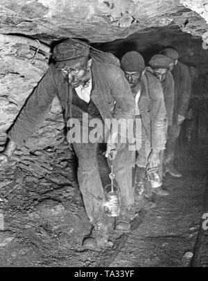 I minatori in un tunnel di bassa nella Saar sulla via del ritorno dal lavoro. I loro volti sono annerite dalla polvere di carbone. Essi portano la mia luci. Foto Stock