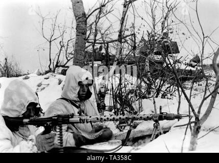 Due soldati tedeschi con un Maschinengewehr 34 hanno preso rifugio in una cava di neve. In background, un distrutto il serbatoio. Foto di Propaganda Company (PK): corrispondente di guerra Krayyvanger. Foto Stock