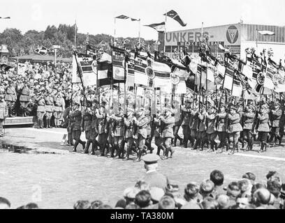 Membri della Stahlhelm con bandiere e uniformi marzo prima della Bundesfuehrer (leader), una banda musicale sulla destra li accompagna. In background, l'aeromobile Junkers e impianto motore. Foto Stock