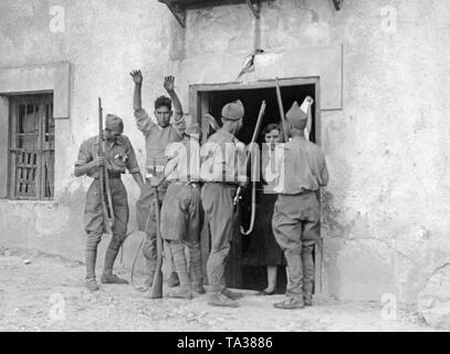 Foto di quattro nazionale spagnolo di soldati nella parte anteriore di una casa colonica in basco di città di confine (Francia) Irun, durante un raid nel settembre 1936. Un uomo e una donna (con un panno bianco) sono esaminate dai soldati per armi nascoste e combattenti repubblicano sono ricercati in casa loro. Foto Stock